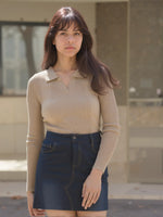 A woman in the 98degreenorth Tuscon Brown Women’s Ribbed Collared Sweater stands outside, looking calmly at the camera.