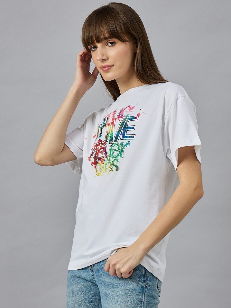 Woman wears 98degreenorth Relax Fit Cotton Typography Graphic T-shirt, standing against a gray background.
