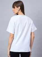 A woman with straight brown hair models the 98degreenorth Typography Print Drop Shoulder T-shirt, back to camera.