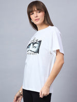 Woman with straight brown hair wears a 98degreenorth Typography Print Drop Shoulder T-shirt and black pants.