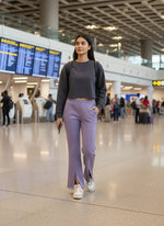 A woman in 98degreenorth Violet Women’s Fleece Flared Sweatpants walks through the airport with a phone and backpack.