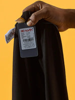 A hand holds 98degreenorth Women Black Ankle-Length Leggings against a yellow background.