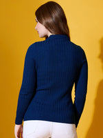 A woman in a 98degreenorth cobalt blue ribbed knit collar sweater and white pants stands against a yellow background.