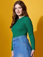 A woman in the 98degreenorth Emerald Green Ribbed Sweater and blue jeans stands before a yellow background.
