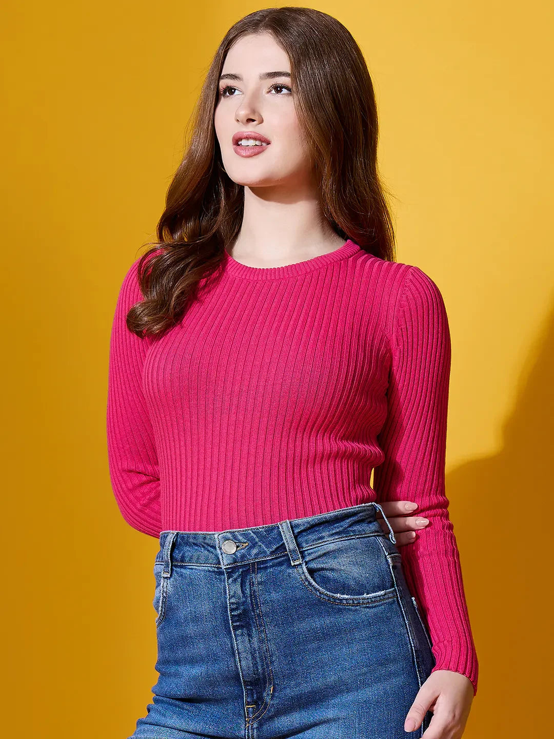 Woman in 98degreenorth fuchsia ribbed sweater, styled for bold winter fashion against a yellow backdrop.