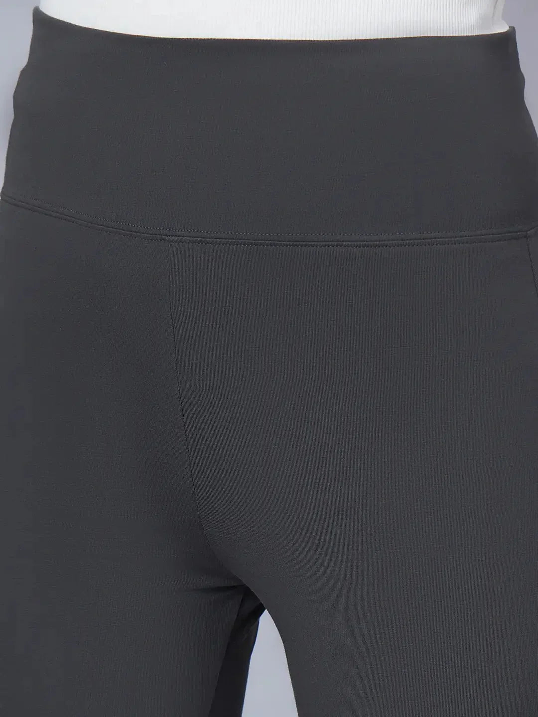 Close-up of a person wearing 98degreenorth Women High-Rise Charcoal Cotton Trousers with a white top, highlighting the stretchable high-rise waistband and upper thighs.