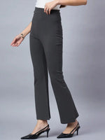 A woman models 98degreenorth Women High-Rise Charcoal Cotton Trousers, styled with a white top, black heels, and a bracelet, set against a plain gray background.