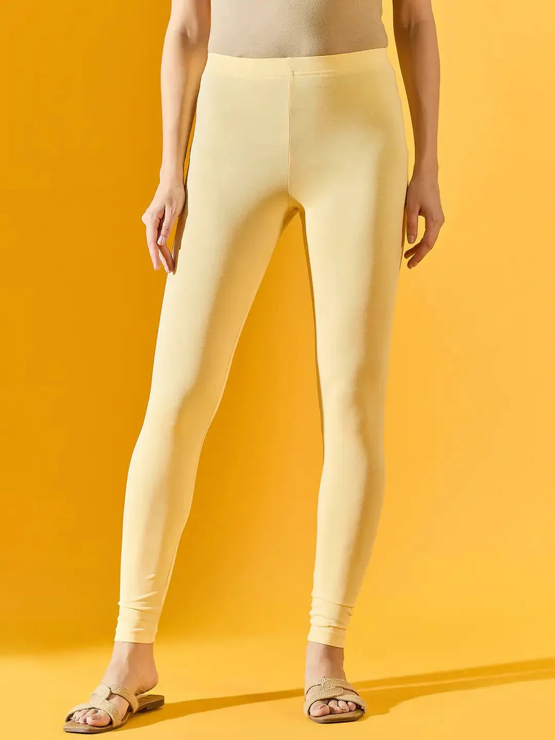 Woman wears 98degreenorth Women Lemon Ankle-Length Leggings and sandals, standing against a yellow background.