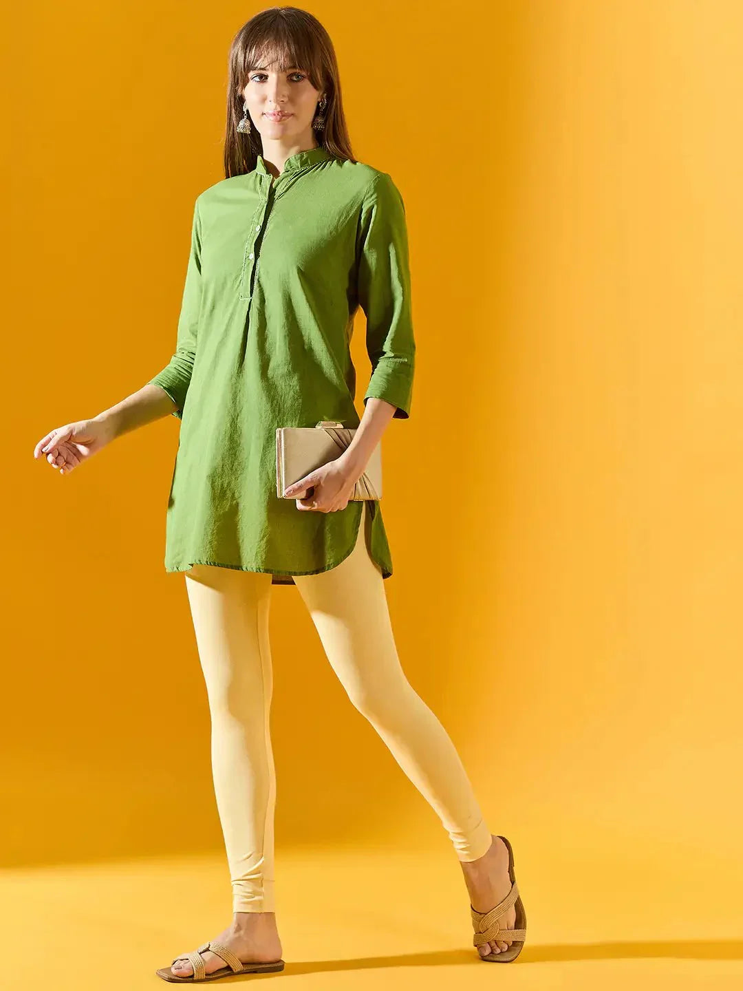 Woman in 98degreenorth Women Lemon Ankle-Length Leggings holds a beige clutch against a yellow background.