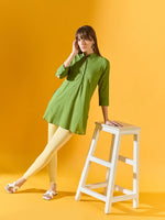 Woman in 98degreenorth Mango Ankle-Length Leggings poses by a white stool against a yellow background.