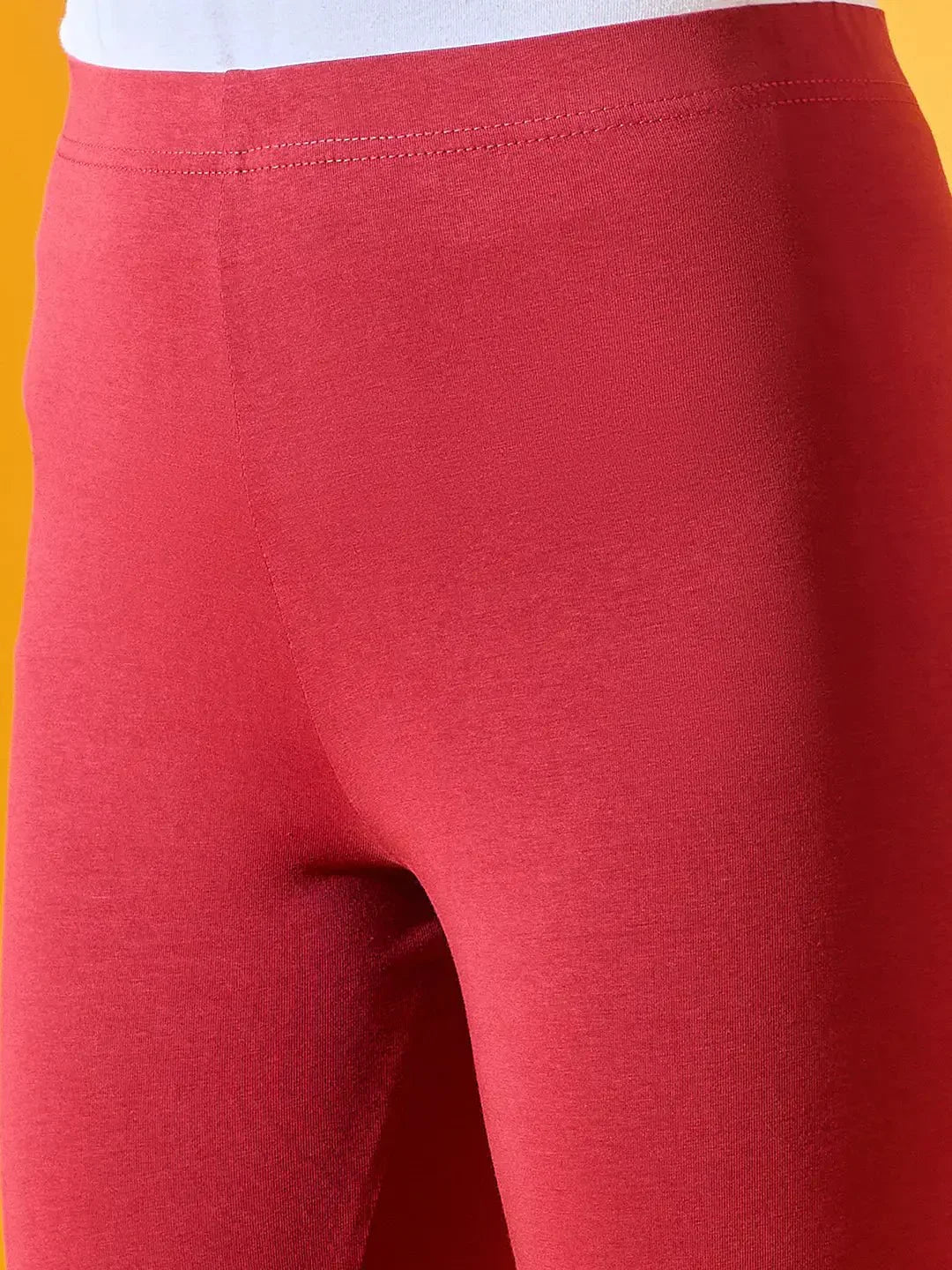 Close-up of 98degreenorth Women Maroon Ankle-Length Leggings with white waistband on a vivid yellow background.