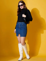 Woman in 98degreenorth Ribbed High Neck Sweater – Black, denim skirt, and sunglasses poses against a yellow background.