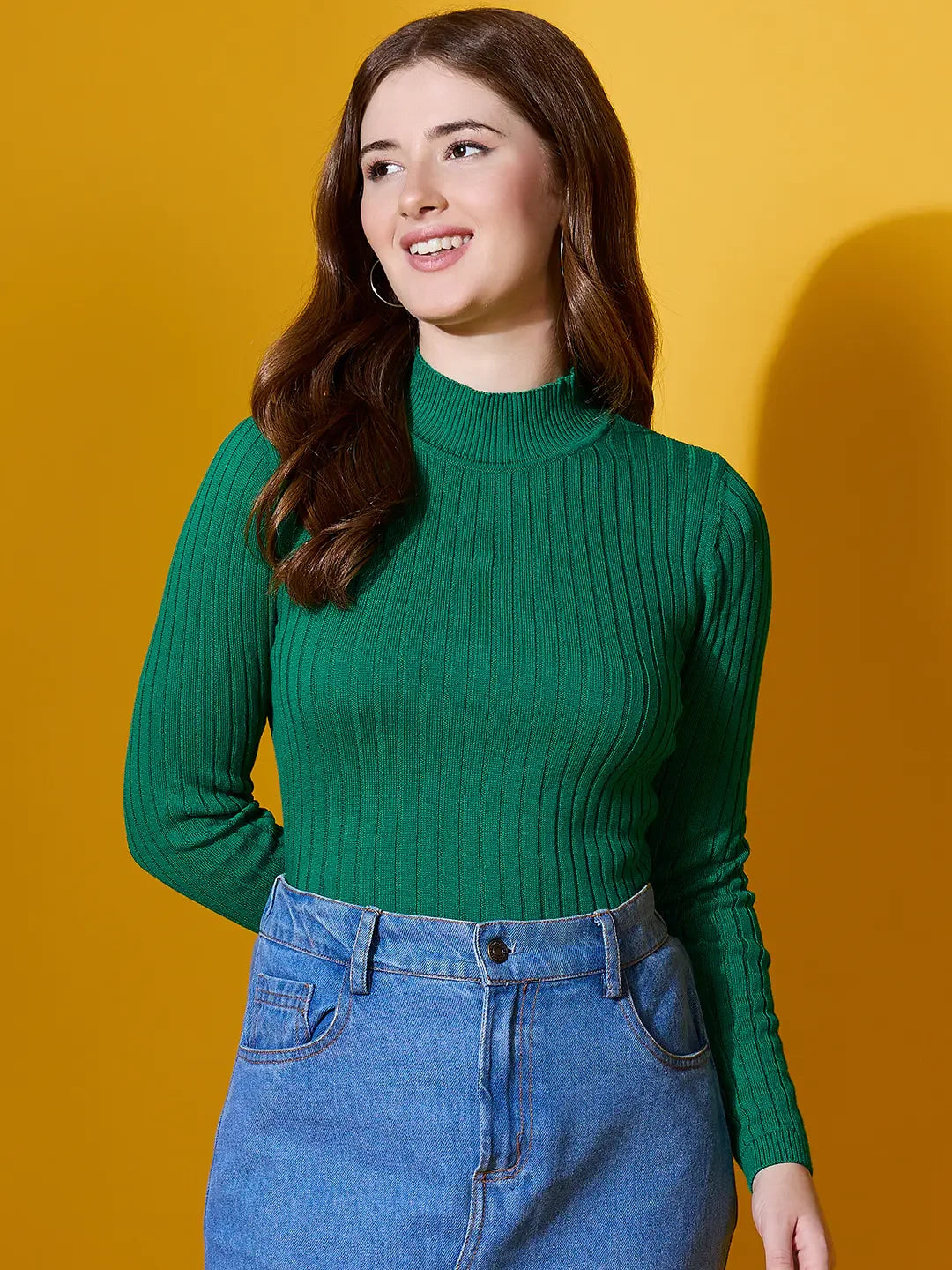 Woman in a 98degreenorth emerald green ribbed high neck sweater smiles against a yellow background.