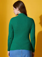 Woman wears 98degreenorth Ribbed High Neck Sweater in emerald green, standing with her back to a yellow background.