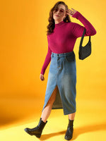 Woman wears 98degreenorth fuchsia ribbed high neck sweater, denim midi skirt, and boots against a yellow background.