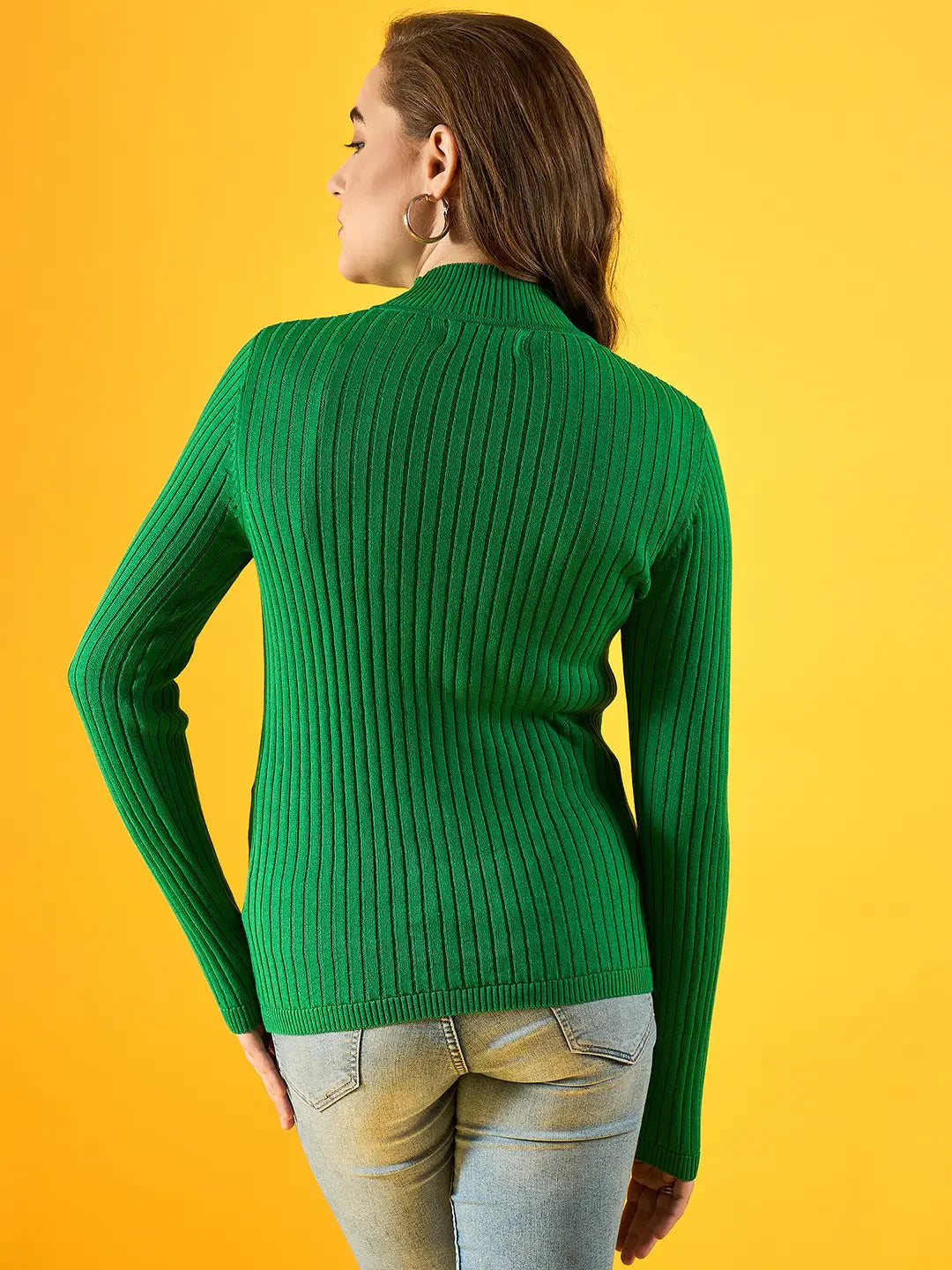 Woman wears 98degreenorth Women Ribbed High Neck Sweater – Green, styled with jeans against a yellow background.