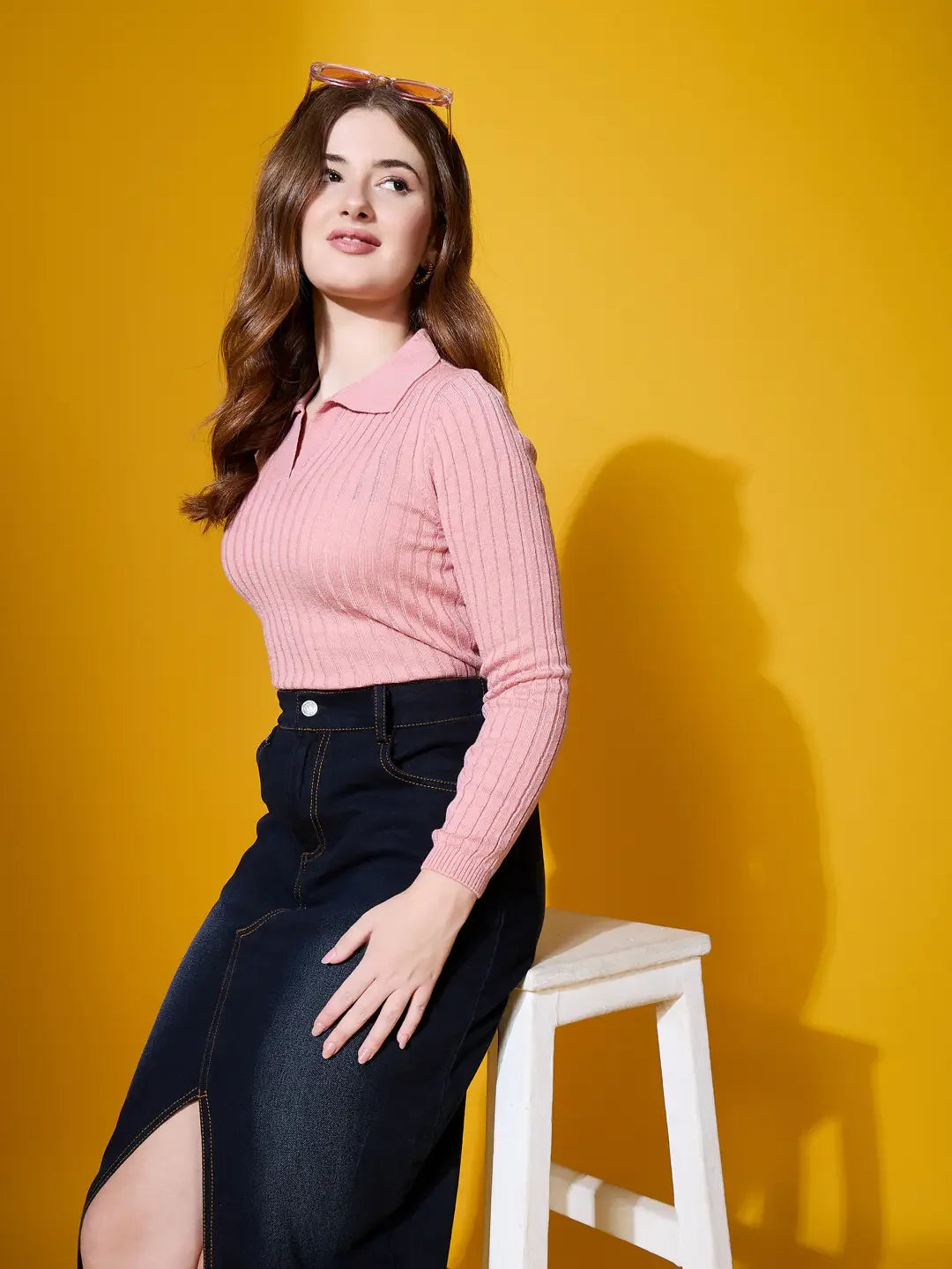 Woman wears 98degreenorth Salmon Ribbed Collar Neck Sweater, seated on a white stool against a yellow background.