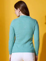 Woman with long brown hair wears a 98degreenorth Sea Green Ribbed Collar Sweater, white pants, on yellow background.