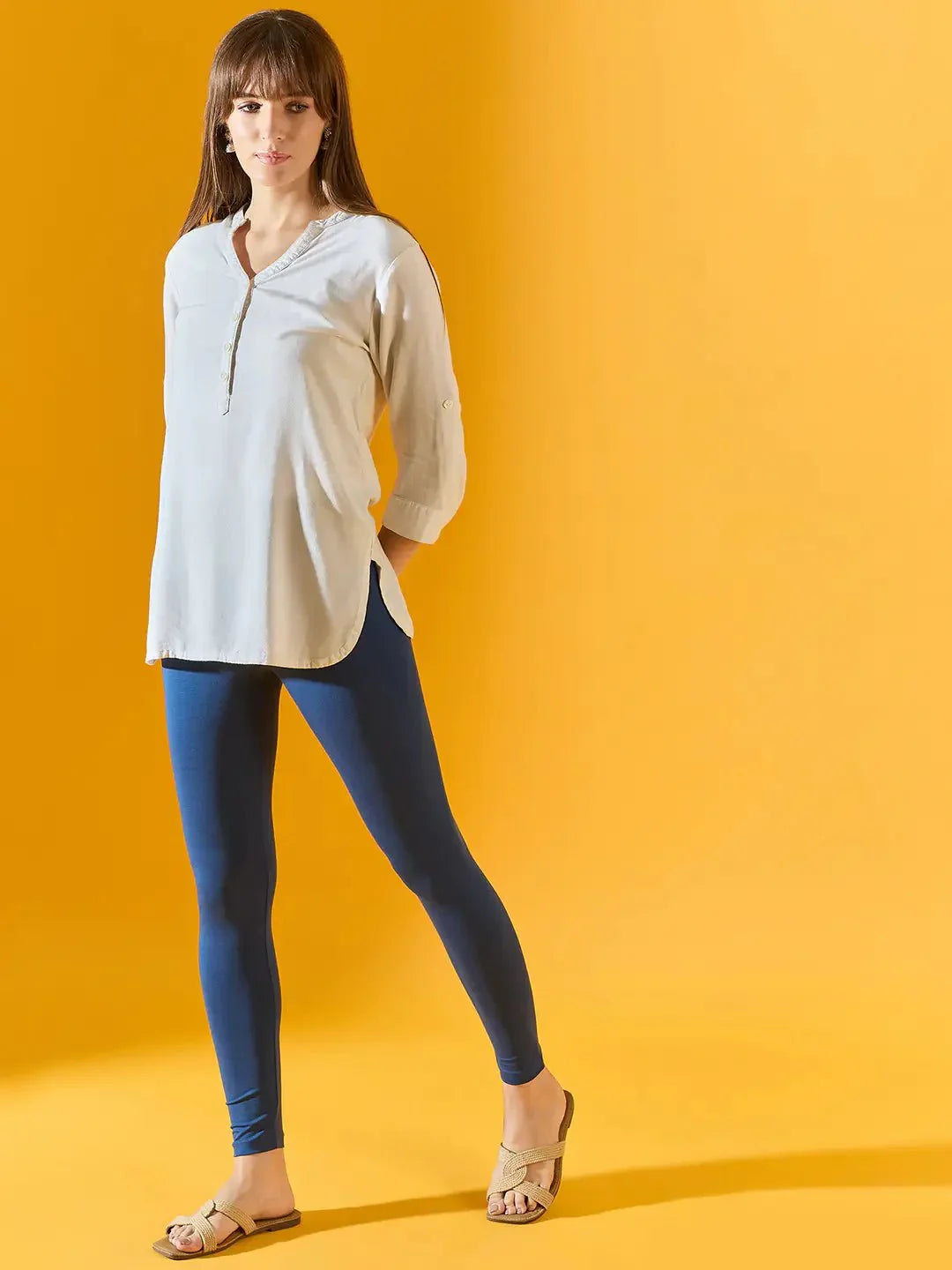 Woman wears 98degreenorth Women Teal Blue Ankle-Length Leggings, posing against a bright yellow background.