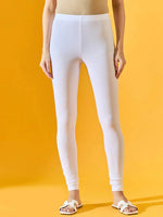 Only the lower half of the body is shown, featuring 98degreenorth’s Women White Ankle-Length Leggings against a yellow background. The model pairs them with a beige top and white sandals for a casual look.
