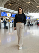 A woman in 98degreenorth Women's Almond Flared Bootcut Sweatpants walks through an airport, phone in hand.