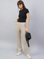 Woman in sunglasses wears 98degreenorth Almond Flared Bootcut High-Waist Lounge Pants, holding a black backpack.
