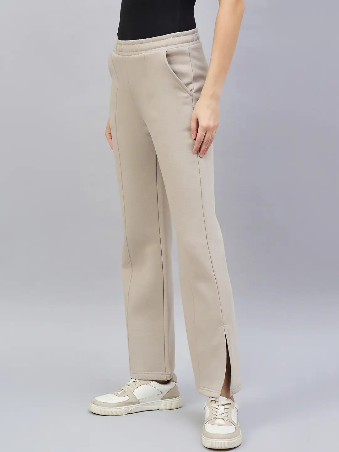 A woman wears 98degreenorth’s almond flared bootcut sweatpants with side slit, paired with white sneakers.