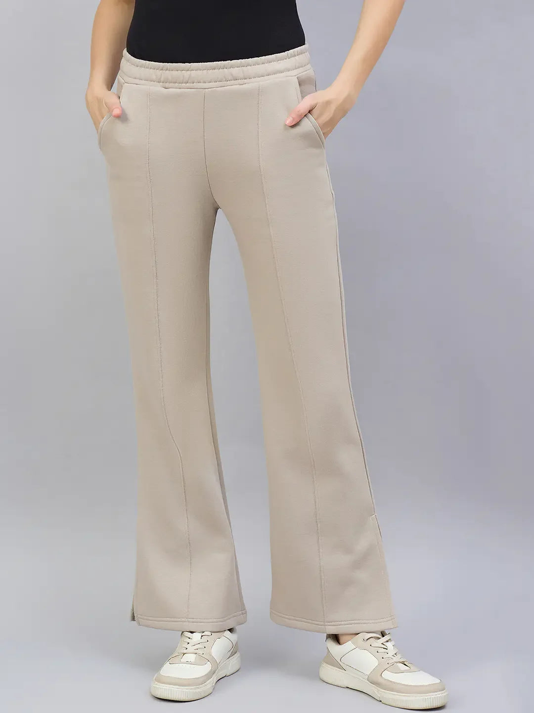 Model in 98degreenorth Women’s Almond Flared Bootcut Sweatpants with side slit, hands in pockets, against plain background.