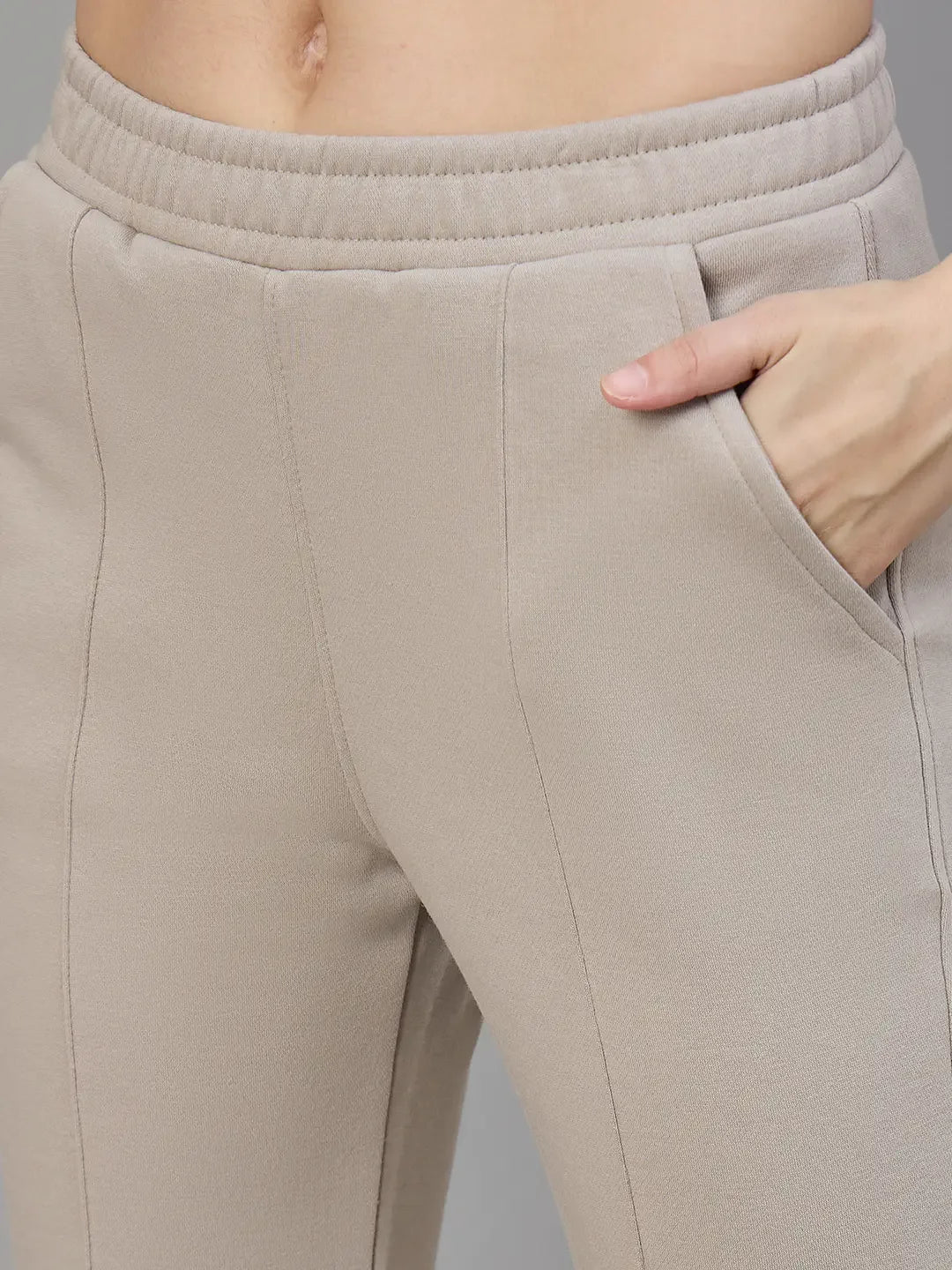 Close-up of a person wearing 98degreenorth Women’s Almond Fleece Flared Sweatpants with a hand in the pocket.