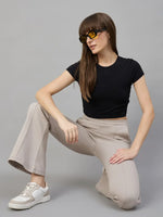 Model in 98degreenorth Women’s Almond Fleece Flared Sweatpants kneels in sunglasses against a gray background.
