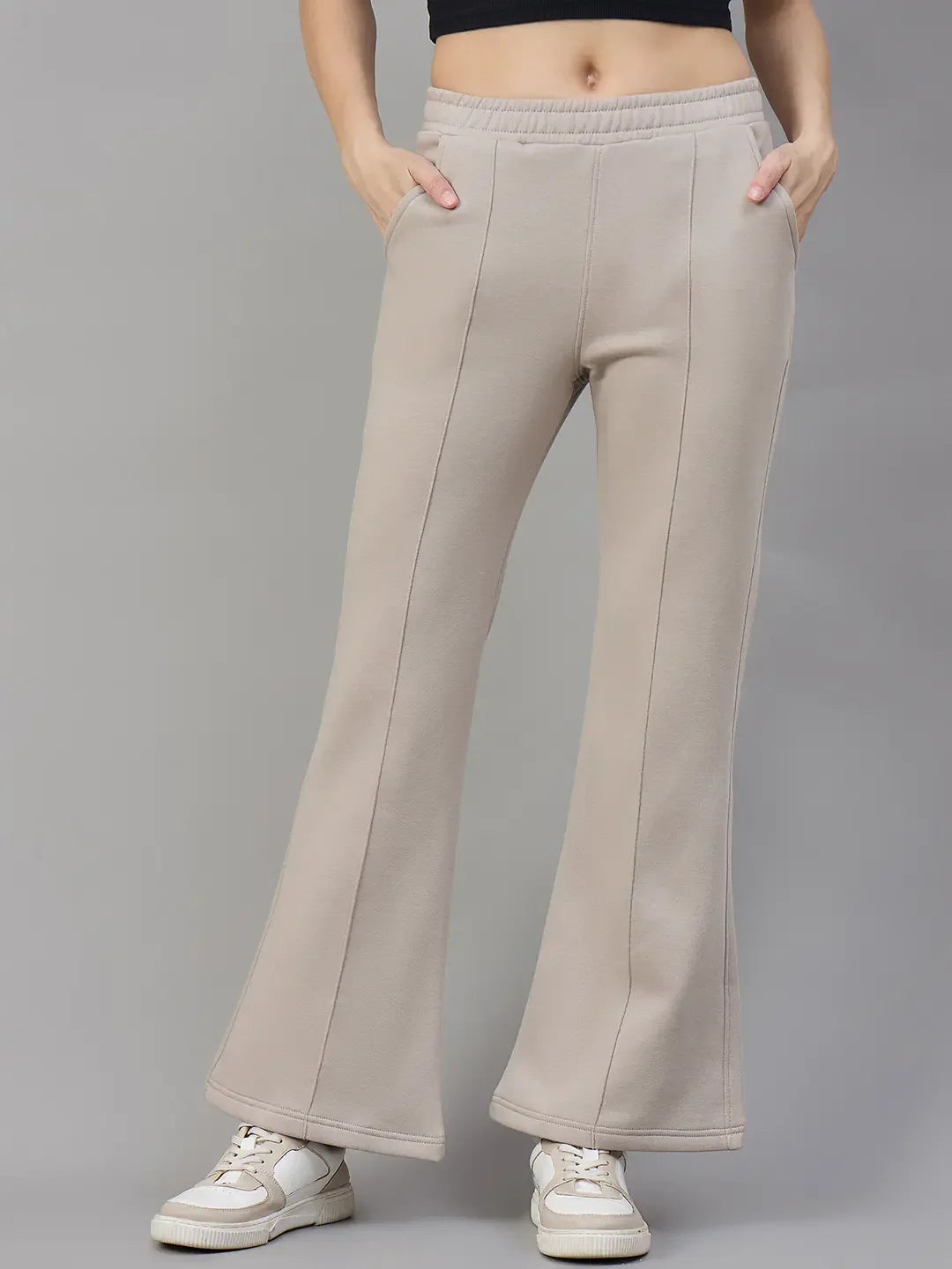 Woman wears 98degreenorth Almond Fleece Flared Sweatpants—high-waisted, cozy winter wear—against a gray background.