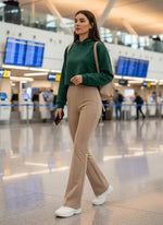 Woman in 98degreenorth Almond Fleece Flared Sweatpants, high waisted and cozy, walks airport terminal, phone in hand.
