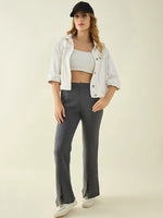 Woman in a white crop top, jacket, and 98degreenorth’s Anthra Flared Bootcut High-Waist Sweatpants with Side Slit.