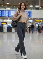 A woman in 98degreenorth Women's Anthra Flared Bootcut Sweatpants with Side Slit walks through an airport, smiling.