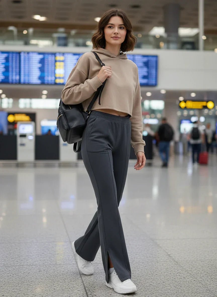 A woman in 98degreenorth Women's Anthra Flared Bootcut Sweatpants with Side Slit walks through an airport, smiling.