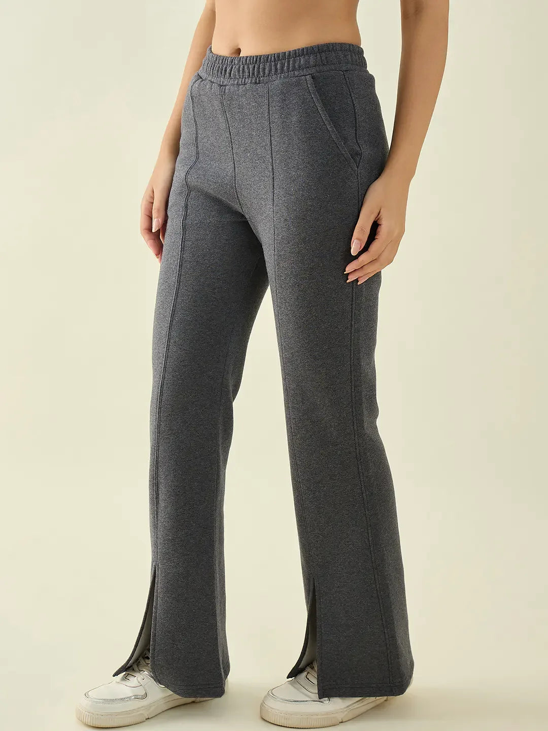 Woman in 98degreenorth Anthra Flared Bootcut Sweatpants with Side Slit, paired with white sneakers, on a light backdrop.