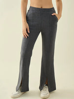 Woman wears 98degreenorth anthra high-waist flared sweatpants with side slits and white sneakers.