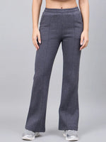 Model in 98degreenorth Women’s Anthra Fleece Flared Sweatpants with white sneakers, posing against a gray background.