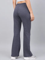 Model wears 98degreenorth Women’s Anthra Fleece Flared Sweatpants, white tank top, and sneakers against a gray backdrop.