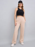 Woman in a black crop top, 98degreenorth beige cotton slim fit trackpants, white sneakers, sunglasses, and black cap.