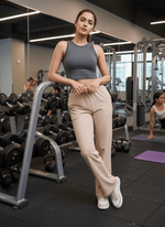 A woman at the gym wears 98degreenorth Women’s Beige Cotton Stretchable Trackpants—high waist, slim fit straight leg.