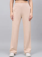 A person wears 98degreenorth Women’s Beige Cotton Stretchable Trackpants, standing against a plain gray background.