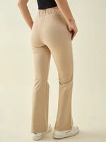 Woman in 98degreenorth Beige Flared Bootcut Cotton Stretchable Trousers, black top, and white sneakers on a light background.