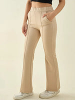 Woman in 98degreenorth Beige Flared Bootcut Cotton Trousers, styled with white sneakers and a black crop top.