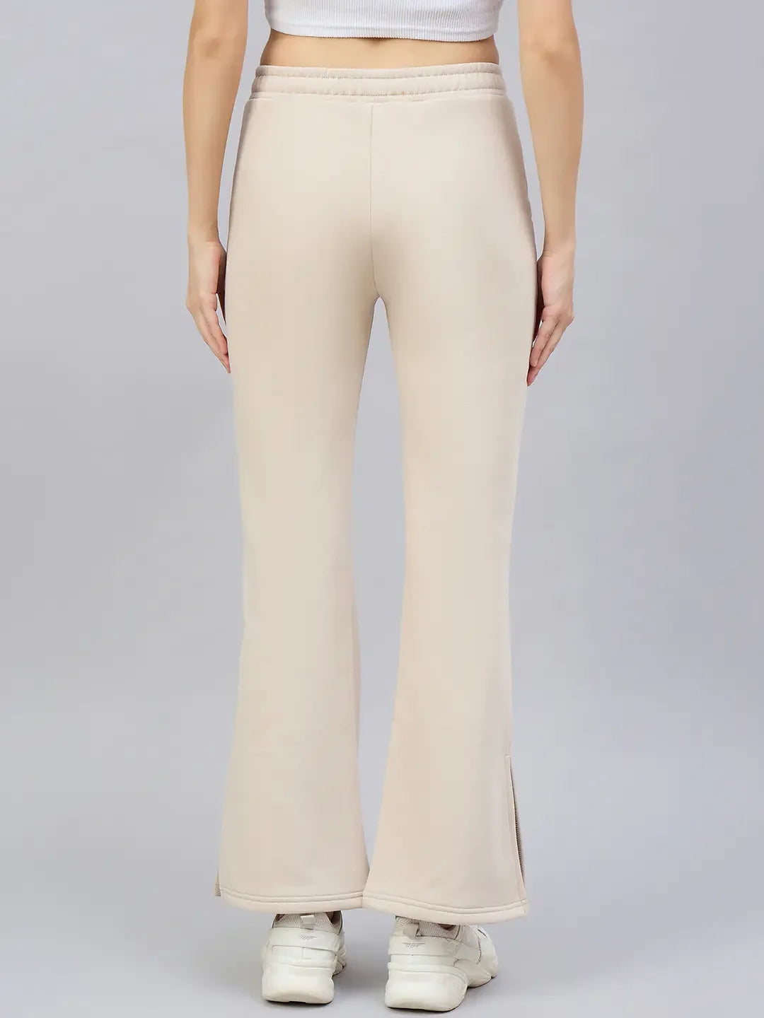 Model in 98degreenorth Women’s Beige Flared Bootcut Sweatpants, shown from the back against a plain gray background.