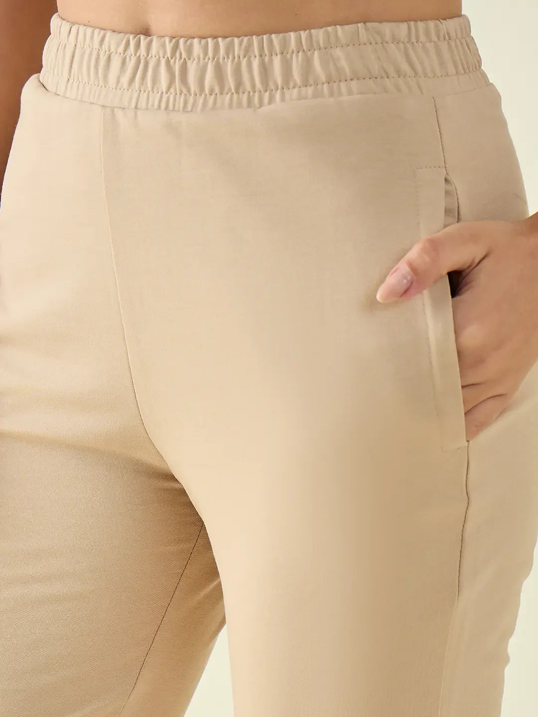 Close-up of a person in 98degreenorth Women’s Beige Flared Fit Bootcut Cotton Stretchable Trousers, hand in pocket.