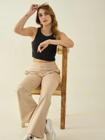 Woman in a black crop top and 98degreenorth Women’s Beige Flared Fit Bootcut Trousers sits, holding sunglasses.