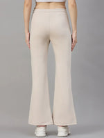 Model in 98degreenorth Women’s Beige Fleece Flared Lounge Pants, shown from the back with white sneakers against gray.