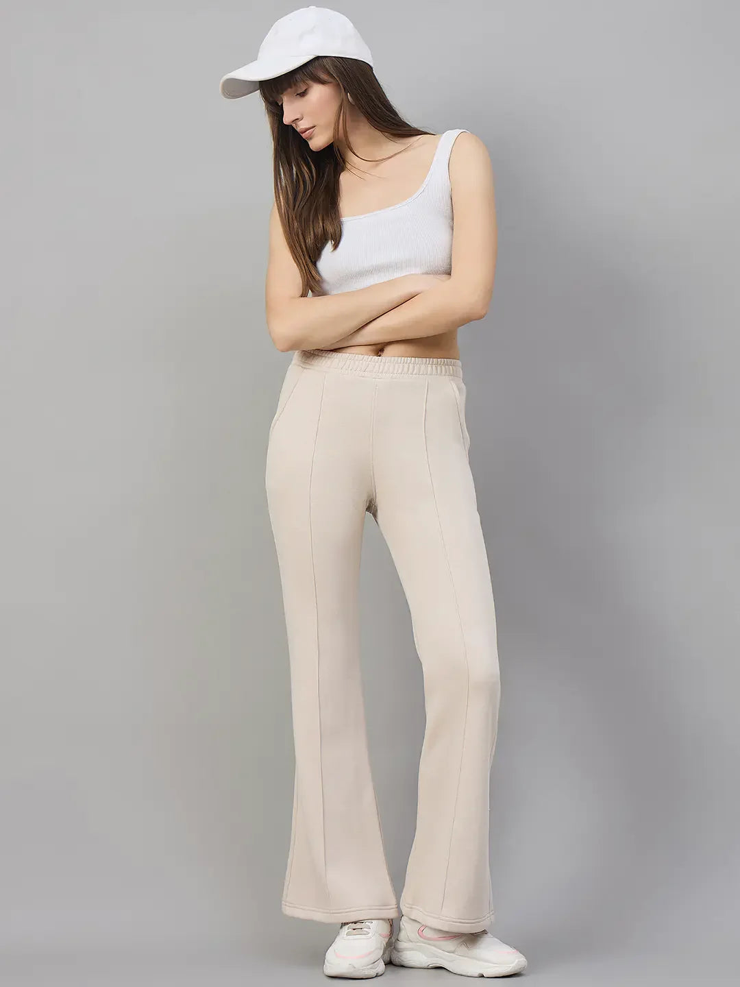 Woman models 98degreenorth Women’s Beige Fleece Flared Lounge Pants, warm & stylish, against a plain gray background.