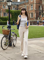 A young woman in 98degreenorth Women’s Beige Fleece Flared Lounge Pants walks on campus, books in hand.